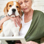 A sad elderly woman hugging a dog