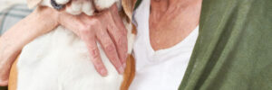 A sad elderly woman hugging a dog
