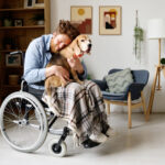 A dog comforting a man in a wheelchair